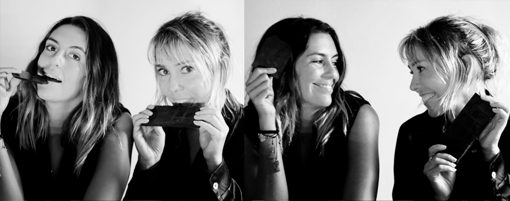 PORTADA FINAAAAAAAL Two women posing with chocolate while smiling and biting the bars of chocolate.
